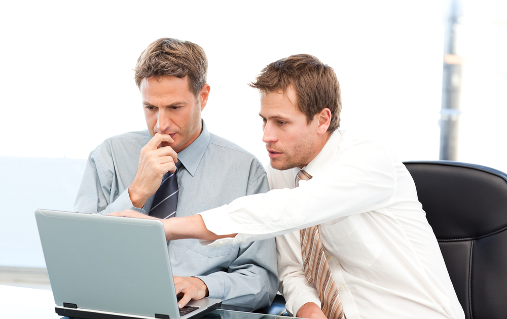 two men working together on a laptop